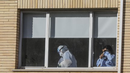 Sanitario con un EPI en la ventana de un hospital