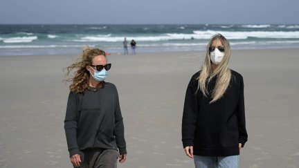 Dos chicas caminan por la playa con mascarilla