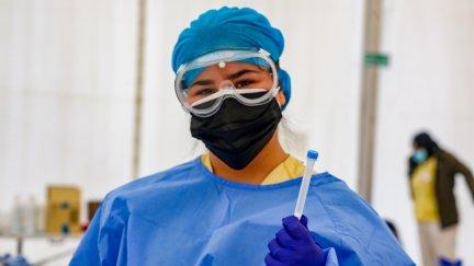 Personal sanitario con EPI y una prueba PCR frente a la COVID-19.