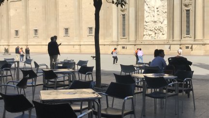 Terraza con mesas y sillas y el Pilar de fondo.