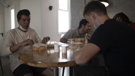 Varias personas comen en un comedor social.