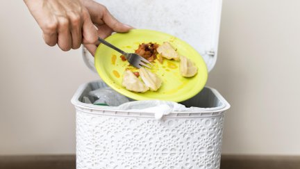 Una persona tira comida a la basura