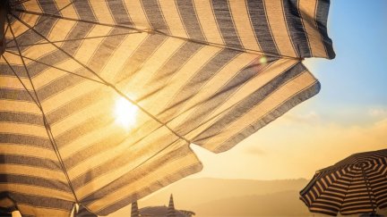 Luz solar atravesando una sombrilla en una playa (Canva)