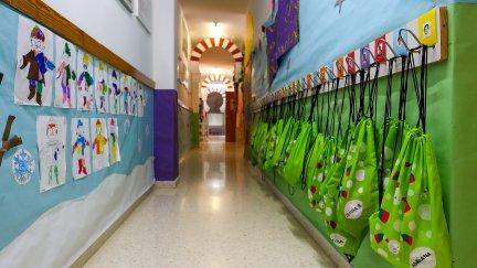 Pasillo con dibujos y mochilas colgadas en un centro de Educación Infantil (EP).