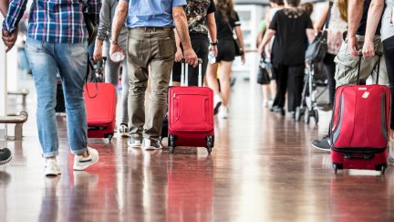 Viajeros con maletas transitan en un aeropuerto.