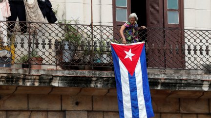 Una mujer coloca la bandera cubana en su balcón.