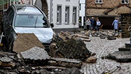 Un coche dañado sobre una carretera destrozada por las inundaciones de Alemania.
