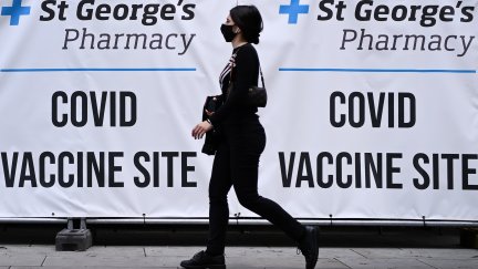 Una mujer pasea frente a un cartel de vacunación contra la COVID-19 en Londres (Reino Unido).