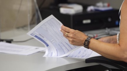 Una empleada hojea varias hojas en su puesto de trabajo de la Oficina de Hacienda (EP).