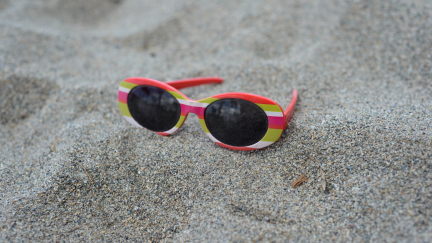 Fotografía de unas gafas de sol de niño en la playa (Canva).
