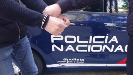 Un policía nacional junto a un detenido.