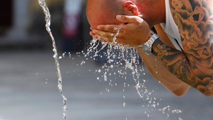 Un hombre se refresca con agua en una fuente (EFE).