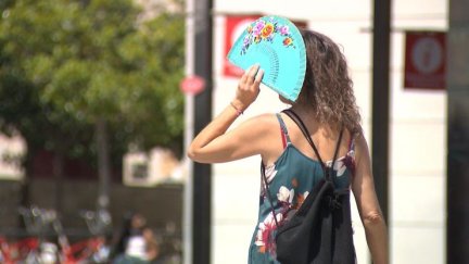 Una mujer se protege del sol con un abanico.