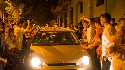 Decenas de personas rodean a un vehículo que circula por una calle del barrio de Gracia en plenas fiestas (EP).