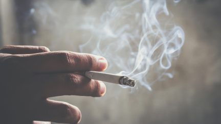 Una mano sostiene un cigarrillo encendido.