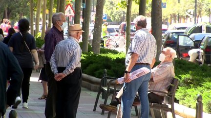 Un grupo de personas mayores conversa en la calle.