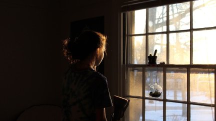 Una niña mira por la ventana.