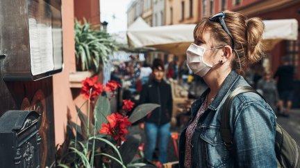 Una mujer con mascarilla lee un cartel en la calle.