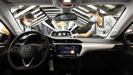 Vista del interior de un coche mientras dos personas desarrollan su trabajo en la planta de Figueruelas. / Foto: EP