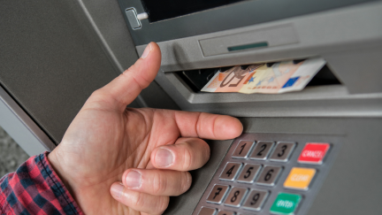 Una persona mayor saca dinero del cajero automático de un banco