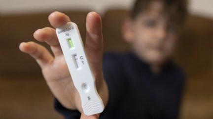 Un niño muestra un test de antígenos negativo.