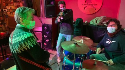 El profesor Carlos Montull apunta a la cámara con su bajo en presencia de dos de sus alumnos durante una sesión de combo.