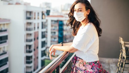 Una mujer con mascarilla se asoma al balcón de su casa durante el confinamiento. / Europa Press