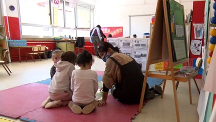 Una profesora dialoga con tres alumnos en el aula.