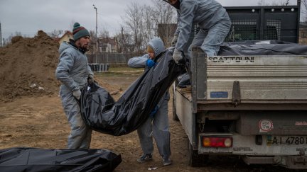 Autoridades forenses recogen cadáveres envueltos en plásticos para su traslado a la morgue en Bucha (Ucrania). / Foto: EFE.
