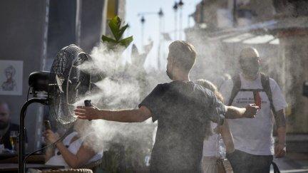 Un chico se refresca con un difusor de vapor de agua de un restaurante.