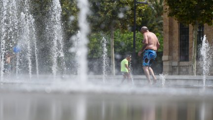 Un hombre y un niño se refrescan en una fuente. / Europa Press