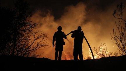 Dos bomberos tratan de reducir las llamas de uno de los incendios que está asolando Grecia. / EFE