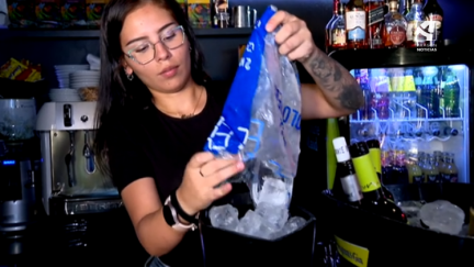Una camarera echa hielos a un cubo.