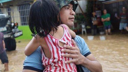 Un policía sujeta a una niña en la operación de rescate en la ciudad de Parang, Maguindanao (Filipinas), afectada por las inundaciones / Foto: Oficina Regional de la Policía Autónoma de Bangsamoro (BAPRO).