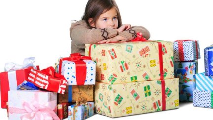 Una niña apoyada en paquetes de regalos. / Canva.