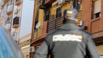 Un agende de Policía Nacional mira en dirección a la vivienda que ha sufrido el incendio en Huelva. / EP.