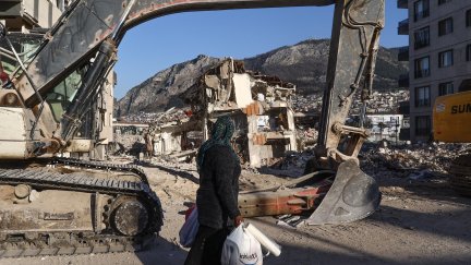 Una mujer pasea junto a un edificio en ruinas de la ciudad de Hatay. / EFE