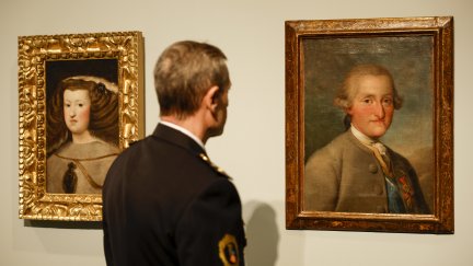 Un agente de la Unidad de Patrimonio de la Policía de la Generalitat contempla los cuadros falsificados de Velázquez 'Mariana de Austria' y de Goya 'Carlos IV'. / EFE