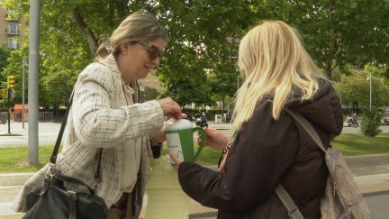 Una persona deposita un donativo en una hucha de la AECC.