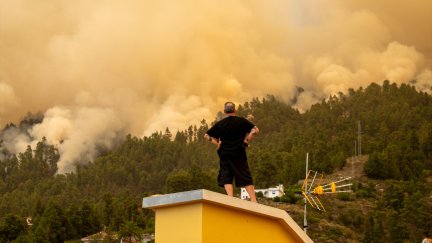 Un vecino observa desde el tejado de una casa el incendio forestal declarado en la Palma. / Europa Press.