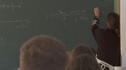 Una profesora escribe en la pizarra en presencia de sus alumnos.