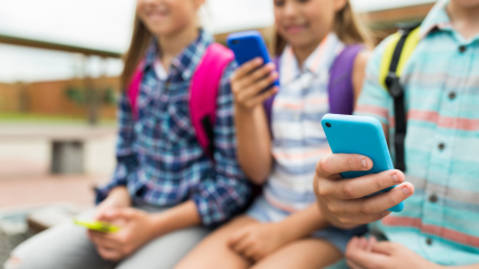 Niños con un teléfono móvil. / Canva