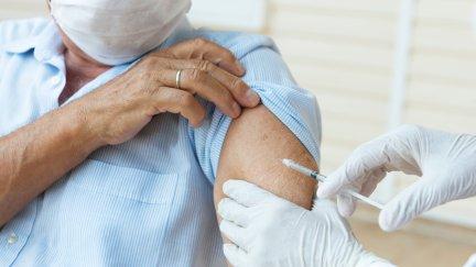 Un sanitario vacunando a una persona. / Canva.