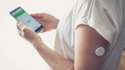 Una mujer lleva un sensor de glucemia en el brazo. / Canva