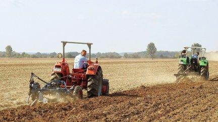 Dos agricultores arando la tierra con sus tractores. / Canva