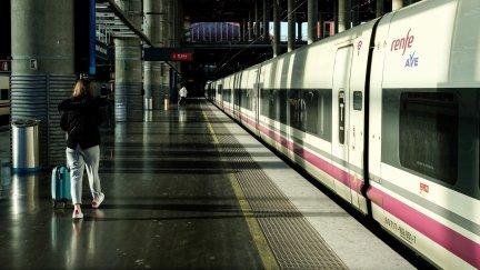 Una mujer camina por el andén junto a un tren de AVE de Renfe estacionado en las vías de la estación de Atocha. / Jesús Hellín- Europa Press