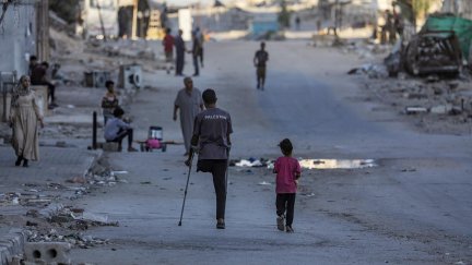 Un hombre palestino amputado camina con su hija por la calle Al Jalaa durante una operación militar israelí en la ciudad de Gaza. / EFE. Mohammed Saber