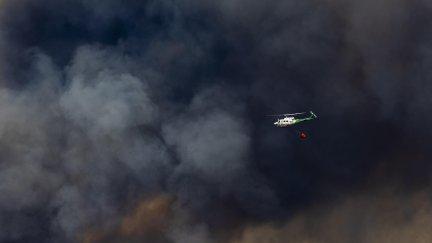 Un helicóptero trabaja en las labores de extinción del incendio forestal en Niebla (Huelva) este sábado, en el que participan veinte medios aéreos, 275 efectivos y 94 vehículos.