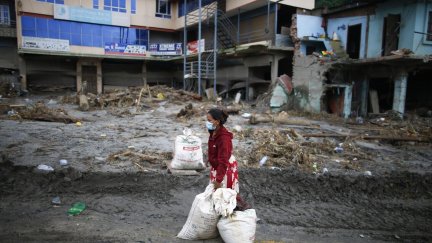 Una mujer espera a que la recojan con sus pertenencias en su casa, situada en una zona afectada por las inundaciones.