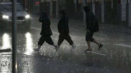 Varias personas caminan empapadas por una calle de Palma.